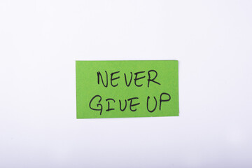 never give up word written on a Green color sticky note with a White background.