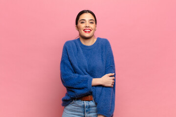 young pretty woman laughing shyly and cheerfully, with a friendly and positive but insecure attitude