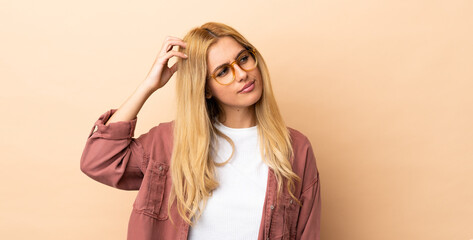 Young Uruguayan blonde woman over isolated background having doubts while scratching head