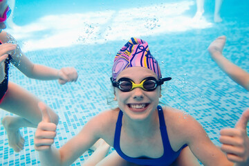 Underwater photo of young friends in swimming pool.