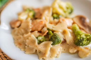 Homemade chicken penne with broccoli on a white plate side view. Close up.