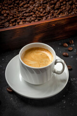 Cup of black coffee and roasted coffee beans in a wooden box vertical photo