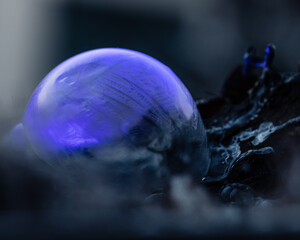 Frozen soap bubble with beautiful light and color on a wooden structure