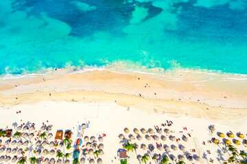 Beach vacation and travel background. Aerial drone view of beautiful atlantic tropical beach with straw umbrellas and palms. Bavaro beach, Punta Cana, Dominican Republic.