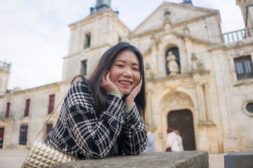 Asian woman enjoying holidays as tourist in Europe - lifestyle portrait of young happy and beautiful Chinese girl in autumn coat touring the city relaxed and cheerful