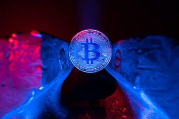 Bitcoin mounted in a steel vise in red and blue light. Keeping Bitcoin safe in crypto wallet....
