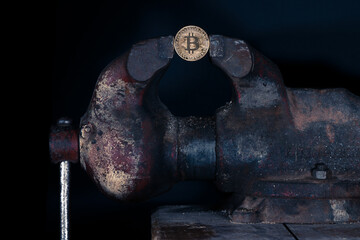 Bitcoin mounted in a steel vise isolated with black background. Keeping Bitcoin safe in crypto...
