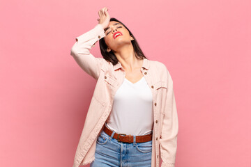 young pretty woman raising palm to forehead thinking oops, after making a stupid mistake or...