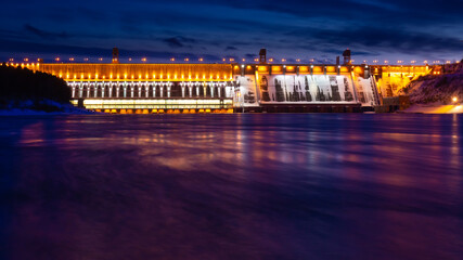 Fototapeta na wymiar Colorful night lights of an illuminated Krasnoyarsk Dam, Russia. Bright view on hydroelectric power station at dusk