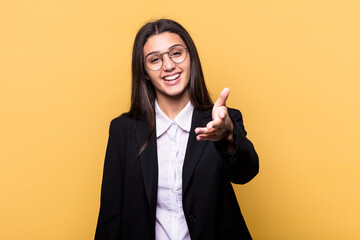 Young Indian business woman isolated on yellow background stretching hand at camera in greeting gesture.