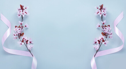 Cherry blossom with pink ribbon and space for text on light grey background. 