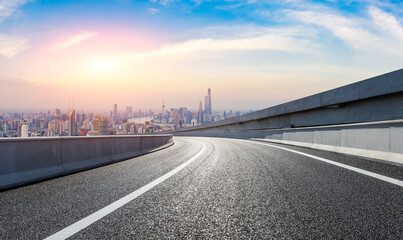 Naklejka premium Empty asphalt road and bridge with city skyline at sunset in Shanghai.