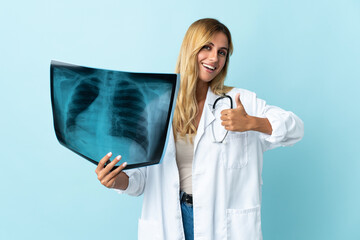 Young blonde Uruguayan doctor woman isolated on blue background giving a thumbs up gesture