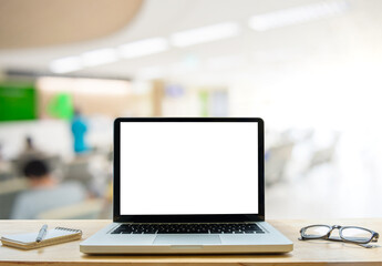 Obraz na płótnie Canvas Desk Laptop with blank screen on table of coffee shop blur