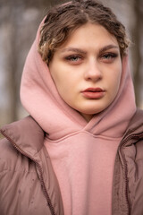 Portrait of a young beautiful girl in a gray jacket in the park, close-up.