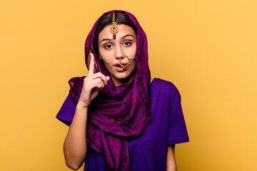 Young Indian woman wearing a traditional sari clothes isolated on yellow background having an idea, inspiration concept.