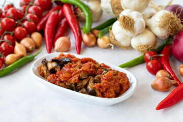 Grilled eggplant salad appetizer with tomato sauce (with eggplant sauce or saksuka). Traditional Middle Eastern meze beside the main course. Layout on white wood