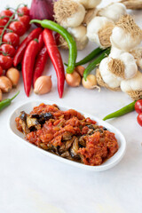 Grilled eggplant salad appetizer with tomato sauce (with eggplant sauce or saksuka). Traditional Middle Eastern meze beside the main course. Layout on white wood