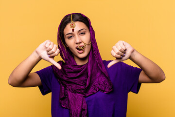 Young Indian woman wearing a traditional sari clothes isolated on yellow background showing thumb down and expressing dislike.