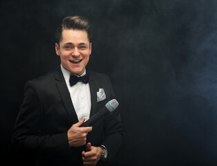 Young handsome man with microphone over black background