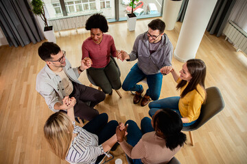 Diverse group of people sitting in circle in group therapy session.