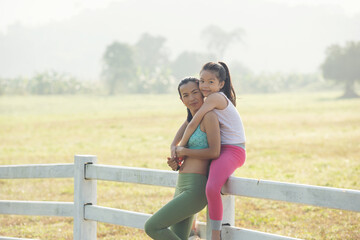 Cute young daughter on a piggy back ride with mother her spending time in countryside