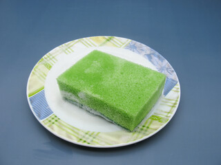 green dish washing sponge with white detergent foam on the plate