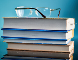 a stack of books and glasses are on the table