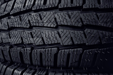 Tires close up. Black studdable winter tyre profile. Car tires in a row.