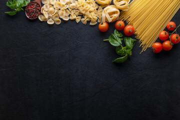 Mixed dried pasta selection on wooden background. composition of healthy food ingredients isolated on black stone background, top view, Flat lay.