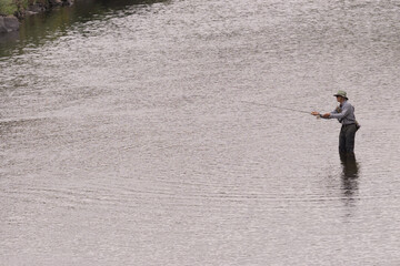Naklejka premium man fishing from afar on river