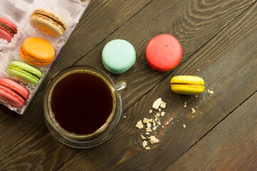 Cup of coffee on a wooden table with macarons, beautiful breakfast concept. Sun ray on a cup of coffee in the morning.