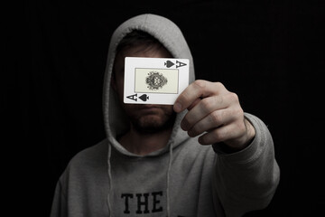 Man in hoodie with playing cards in his hand 