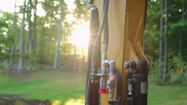 Hydraulic Bucket Cylinder on Excavator and Sun Shining Through Trees in Forest