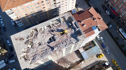 Aerial view of building demolition in the city center. The excavator is on the top floor of the apartment building. The camera is approaching the work machine.  © abu