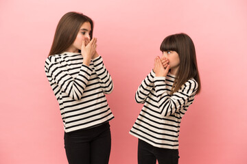 Little sisters girls isolated on pink background covering mouth with hands for saying something inappropriate