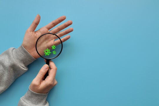 A person examines his hands under a magnifying glass and sees viruses. Fear of disease and infection. Protection and prevention of the disease