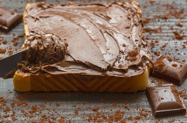 Chocolate spread on bread with a knife. This chocolate is made from hazelnuts and hazelnut paste. The taste of chocolate is very good. 