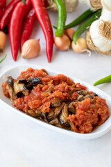 Grilled eggplant salad appetizer with tomato sauce (with eggplant sauce or saksuka). Traditional Middle Eastern meze beside the main course. Layout on white wood