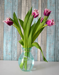 Spring still life with bouquet of lilac fringed tulips in glass bowl on white table. Interior decorations. Vertical view 
