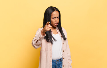 young black woman pointing at camera with an angry aggressive expression looking like a furious,...