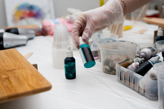 artist holds in his hand a bottle with colored dyes (pigments) for creativity with his own hands, with epoxy resin or paints