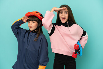 Little sisters practicing cycling and skater isolated on blue background has just realized something and has intending the solution
