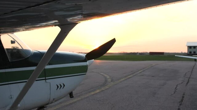 Slider shot of small aircraft parked on a ramp before takeoff, sun setting