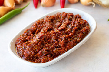 spicy crush or adjika appetizer (harissa) made with tomato, pepper, garlic, onion, pepper paste and olive oil. Acılı ezme