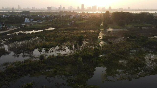 Sunset time over countryside and floaded fields, in the background the city of Phnom Penh, Cambodia