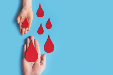 World hemophilia day concept with red blood drop simbol and hands on blue background