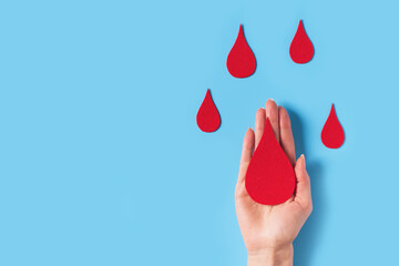World hemophilia day concept with red blood drop simbol and hands on blue background - obrazy, fototapety, plakaty