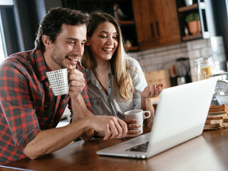 Loving couple drinking coffe in the kitchen. Happy smiling woman enjoy in the morning with her boyfriend..