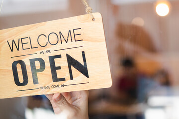 Hand of woman owner retail,coffee shop woman turning sign board to open with wearing face mask ,protection to pandemic of coronavirus reopen store,restaurant after close lockdown quarantine in covid.